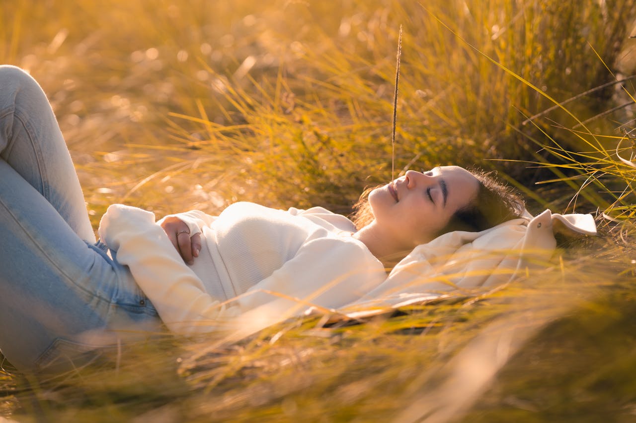 A serene scene of a woman resting in a sunlit golden field, exuding tranquility.